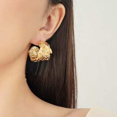 Boucle d'oreille dorée représentée à l'oreille d'une femme brune.