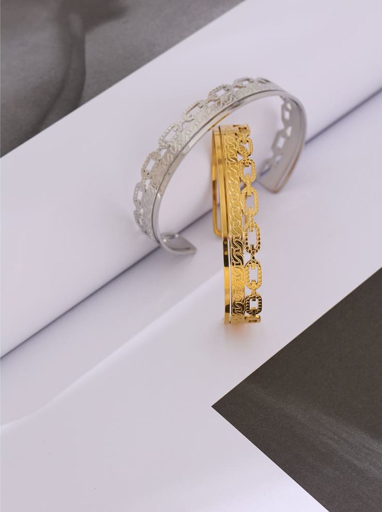 2 bracelets doré et argent posés sur un montant blanc.